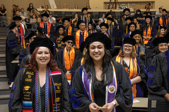 Students posing for a photo wearing graduation attire.