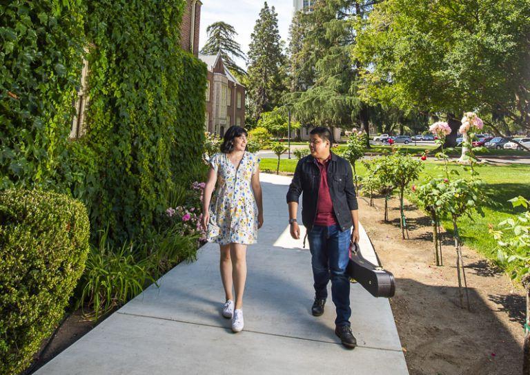 拿着大提琴盒的男学生和走在爬满常春藤的砖拱下的女学生