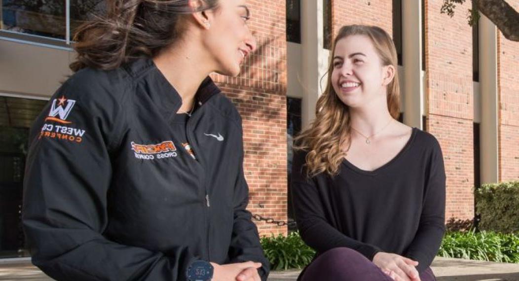 two students sitting on a ledge and talking