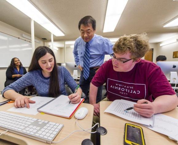 students working at a table with a faculty member helping